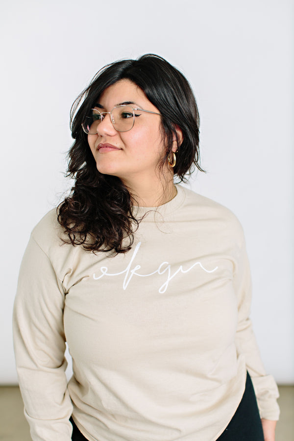 Okanagan Lifestyle beige long sleeve shirt with OKGN printed on front in cursive font