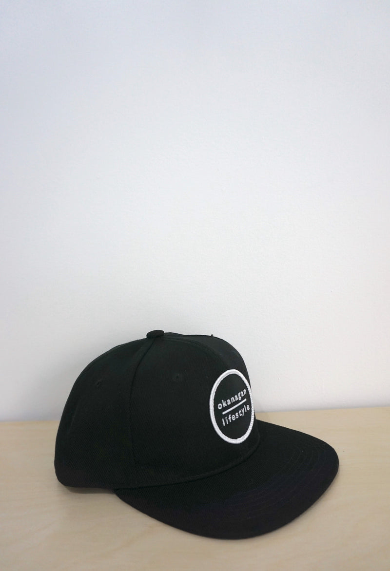 The Classic Okanagan Lifestyle wordmark logo embroidered white on our favorite youth size black snapback