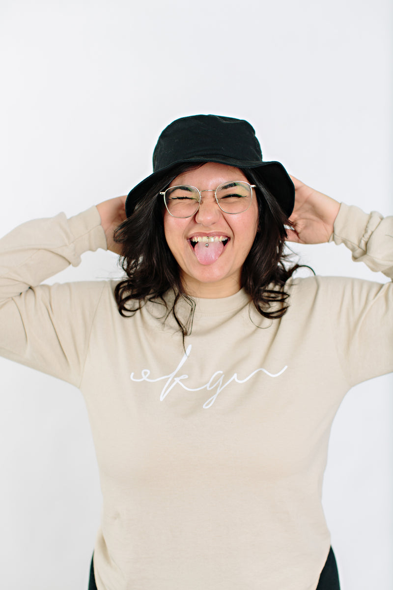 Okanagan Lifestyle beige long sleeve shirt with OKGN printed on front in cursive font